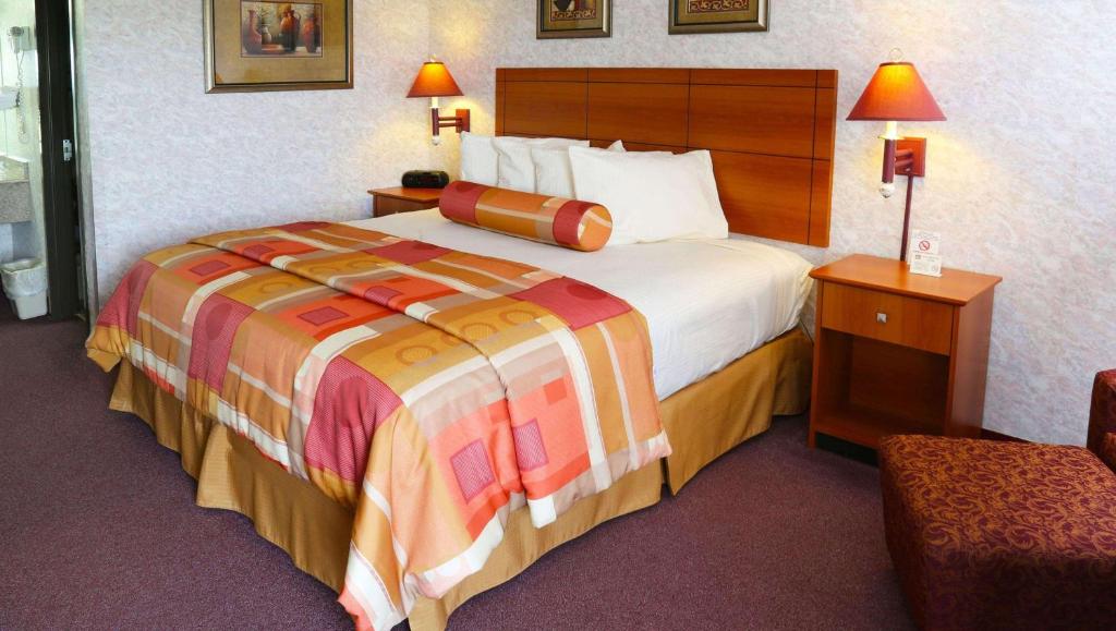 ein Hotelzimmer mit einem großen Bett und einem Stuhl in der Unterkunft Magnuson Hotel Howell/Brighton in Howell