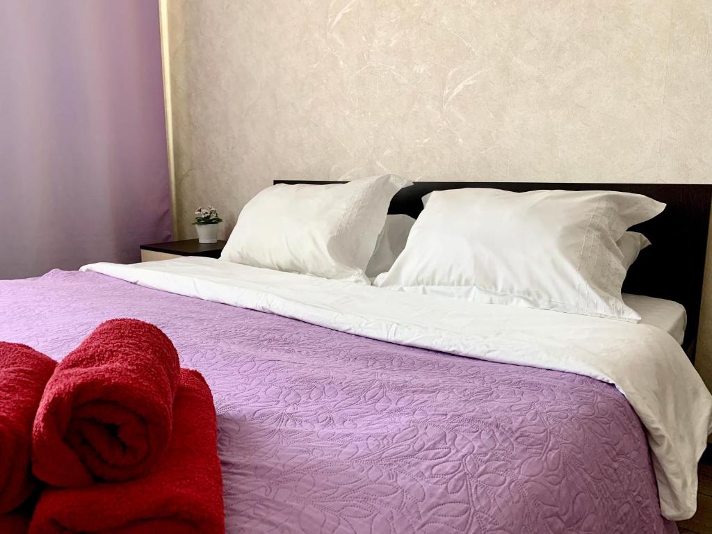 Una cama con almohadas blancas y toallas rojas. en Люкс на Гаражной почти в центре, en Krasnodar