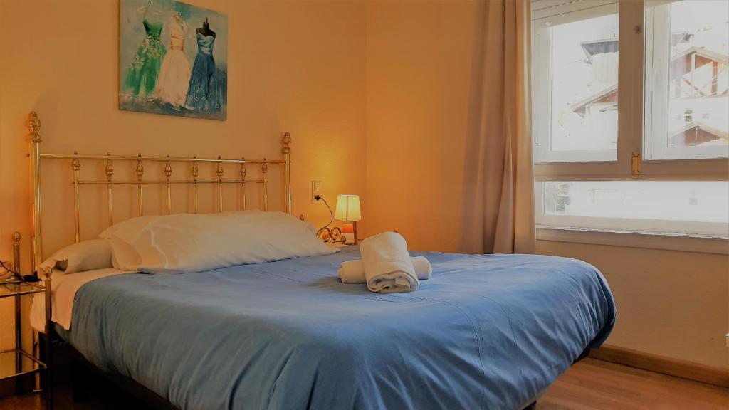 a bedroom with a bed with blue sheets and a window at TODOSIERRANEVADA ZONA BAJA - EDIFICIO ALHAMBRA - Junto a los Telecabinas in Sierra Nevada