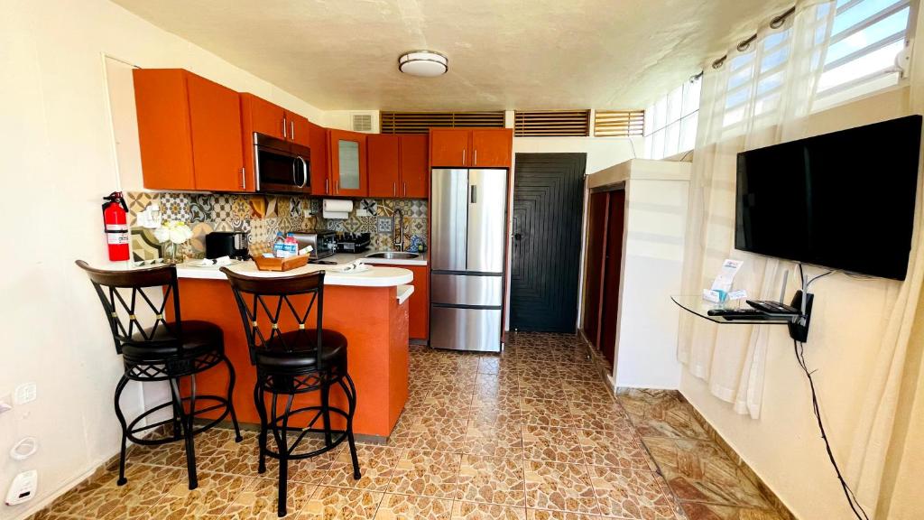 una cocina con armarios naranjas y un bar con taburetes en Cozy Studio Retreat with Private Parking and FREE Laundry en Ponce