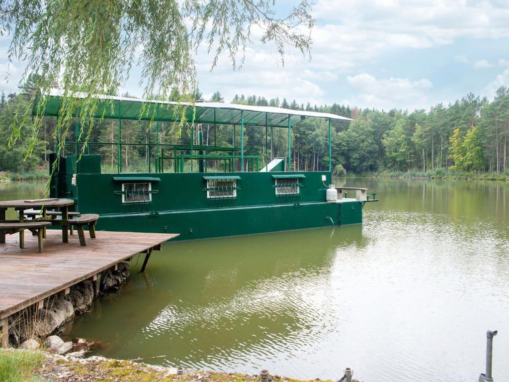 un barco verde está atracado en un lago en Comfy Houseboat in Florennes next to the Forest, en Florennes