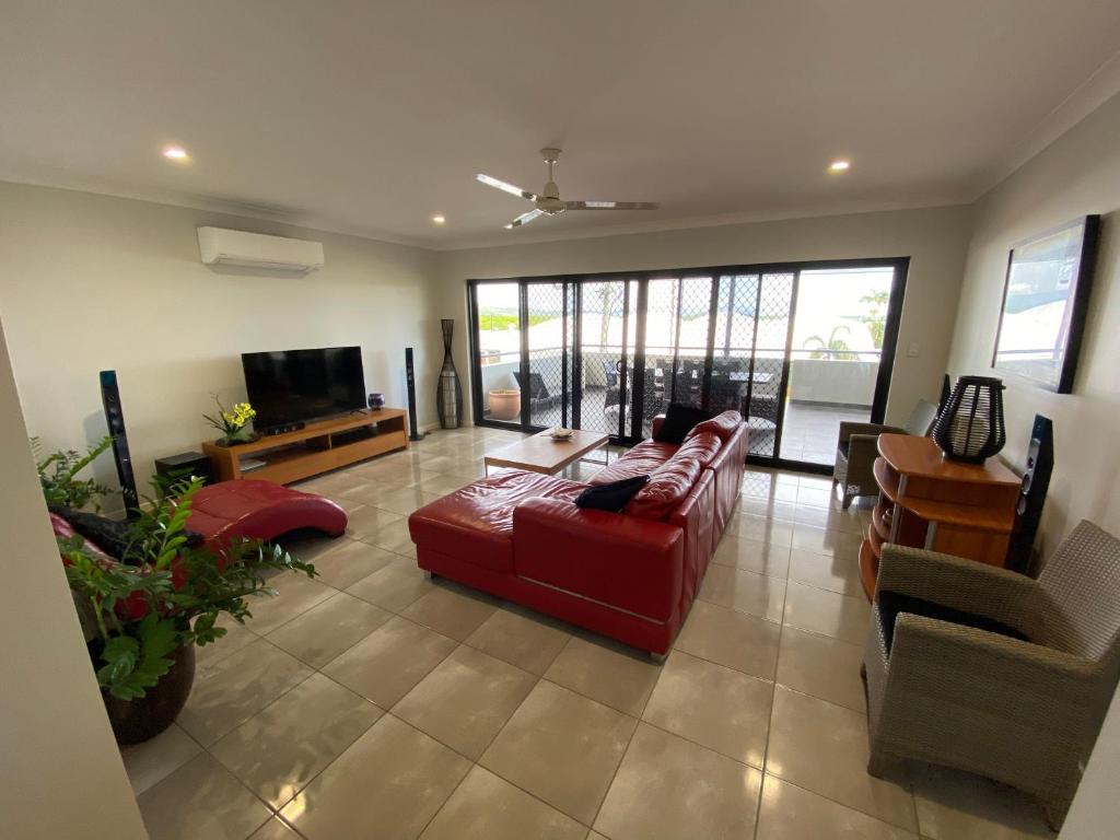 a living room with a red couch and a tv at Cooktown Harbour View Luxury Apartments in Cooktown