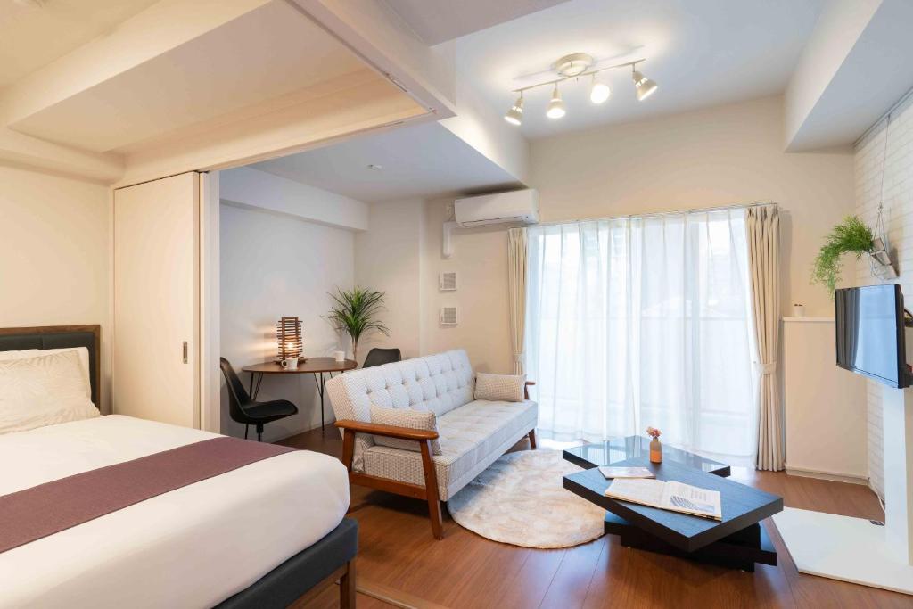 une chambre d'hôtel avec un lit, un canapé et une fenêtre dans l'établissement BON Condominium Umeda, à Osaka