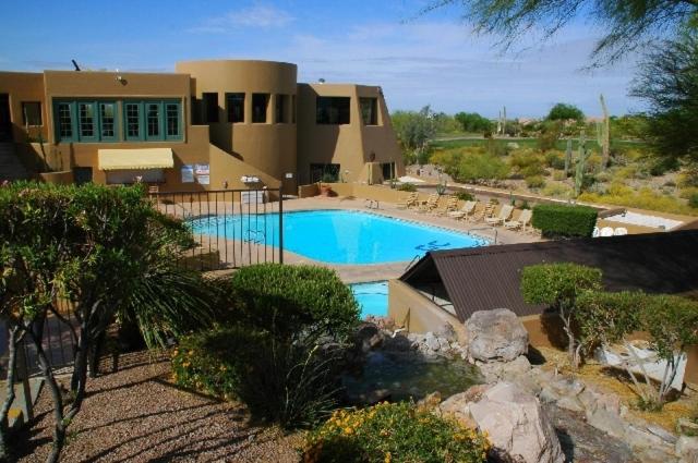 a building with a swimming pool in front of a house at Gold Canyon Golf Resort in Gold Canyon