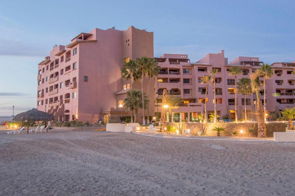 a large building on a beach with palm trees at Marina Pinacate B-102 in Puerto Peñasco