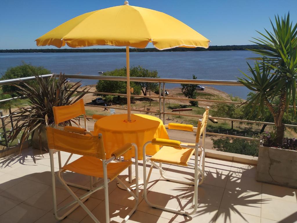 una mesa amarilla y sillas bajo una sombrilla en el balcón en north beach depto 6 en Colón