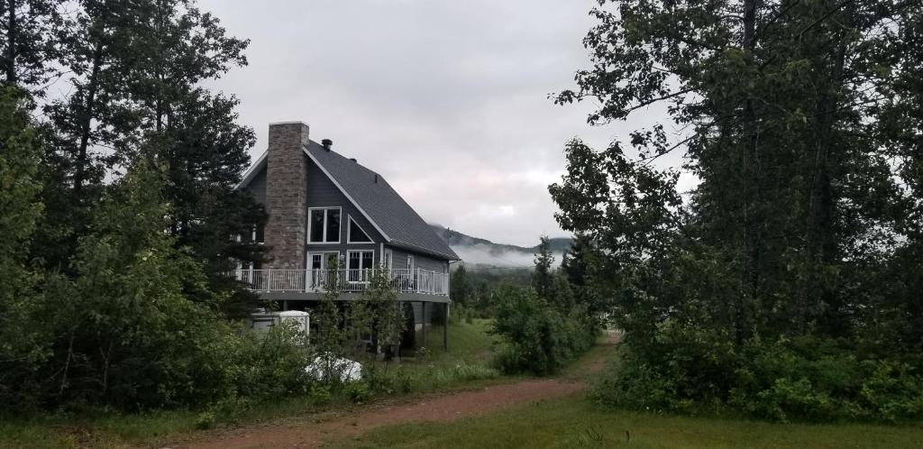 a house on a hill with a dirt road in front at Condo-chalet de la Vallée d'Édouard in LʼAnse-Saint-Jean