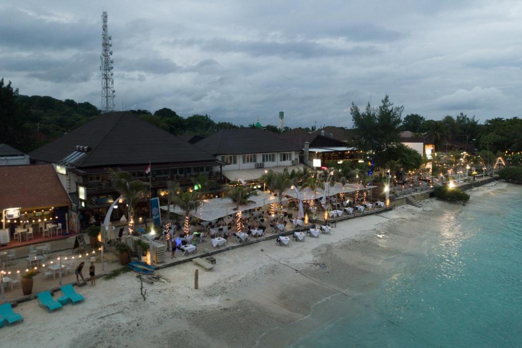 a group of people sitting on a beach near the water at Scallywags Resort in Gili Trawangan