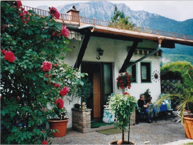 a man sitting in front of a house with flowers at Ferienwohnung Meister in Bad Reichenhall