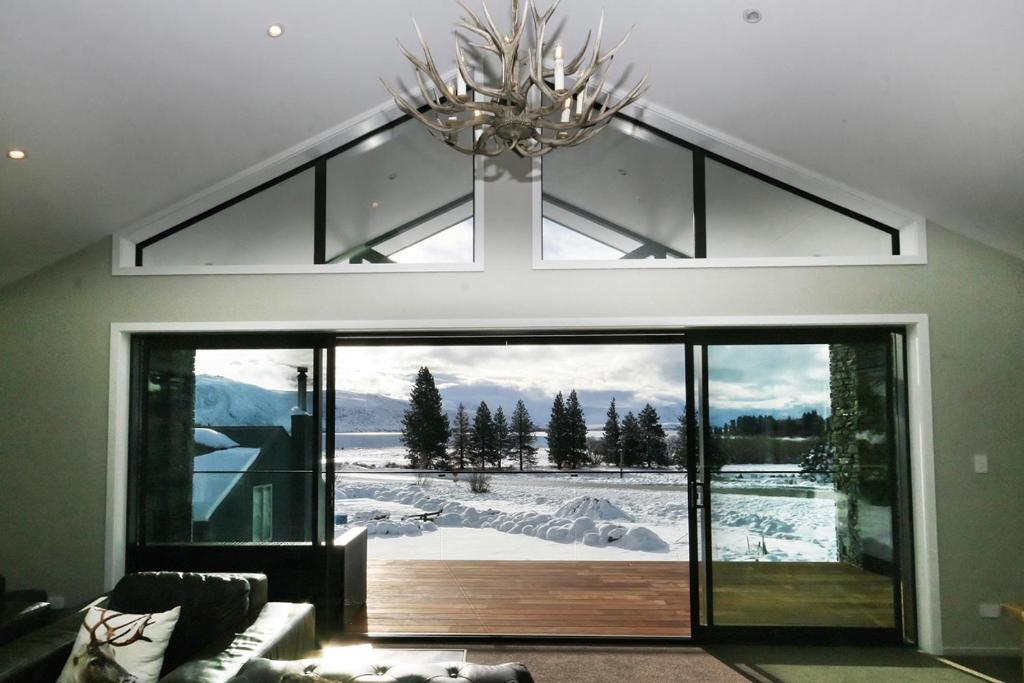 a living room with a large glass door with a view at Lake Views at Antler Lodge in Lake Tekapo