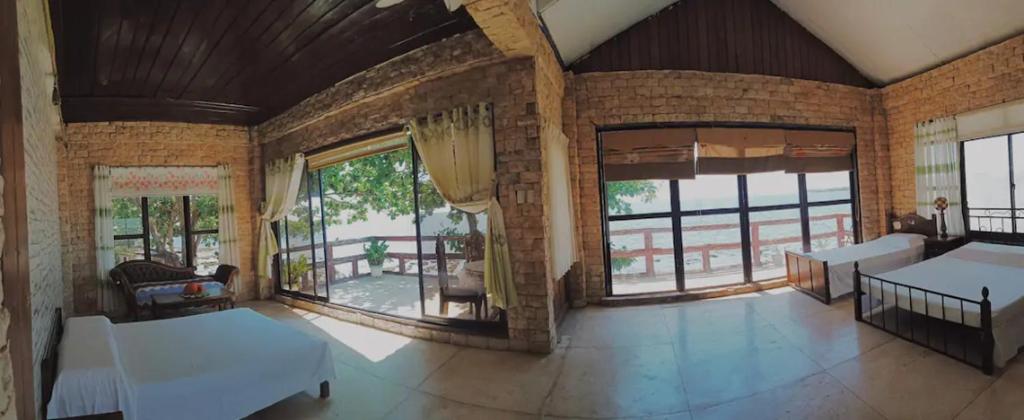 salon z dużymi oknami i ceglaną ścianą w obiekcie RedDoorz Hostel Hardin De Corales La Union w mieście San Fernando