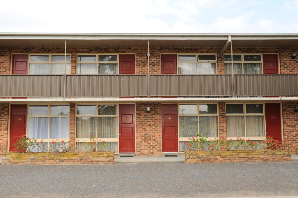 un edificio de ladrillo con puertas y ventanas rojas en Peninsula Motor Inn, en Tyabb