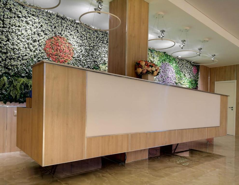 a reception counter in a lobby with flowers on the wall at Central Hotel in Kurgan