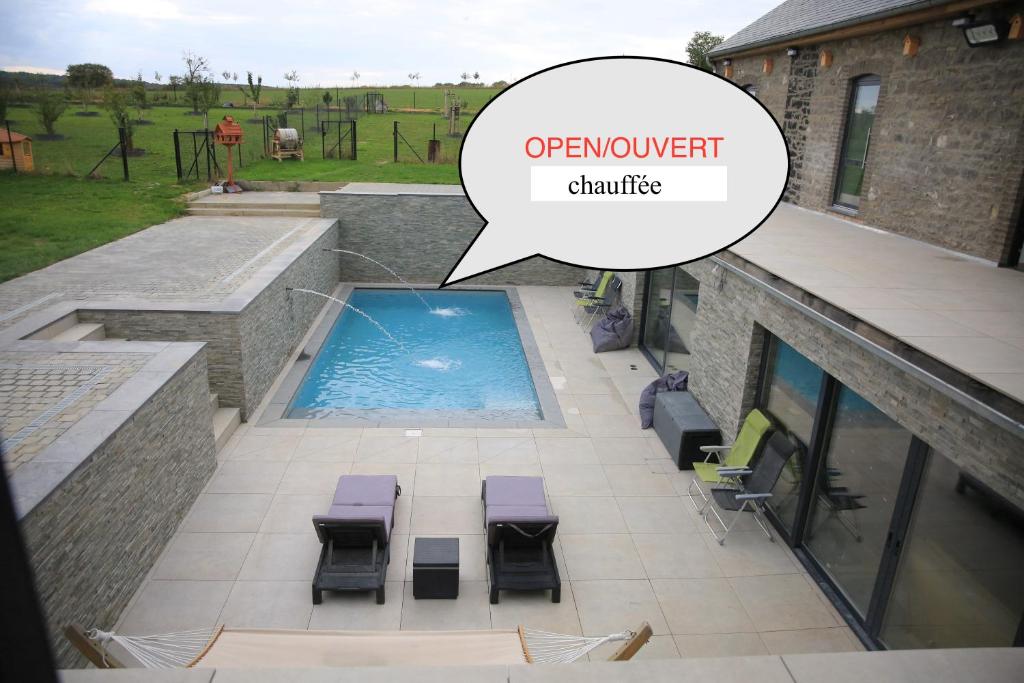 una vista aérea de un patio con piscina y una burbuja de habla diciendo mejora en Durbuy House le Noyer, en Durbuy