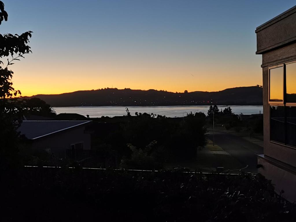 a sunset over a body of water with a building at Lake Taupo Holiday Home in Taupo