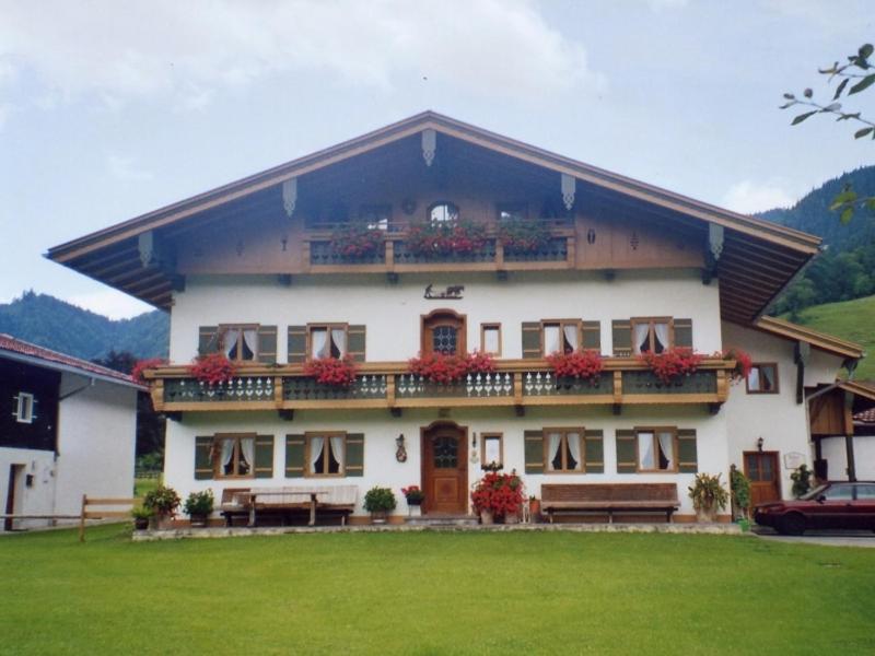 un gran edificio blanco con bancos delante en Ferienwohnung Schmid-Hof, en Oberwössen