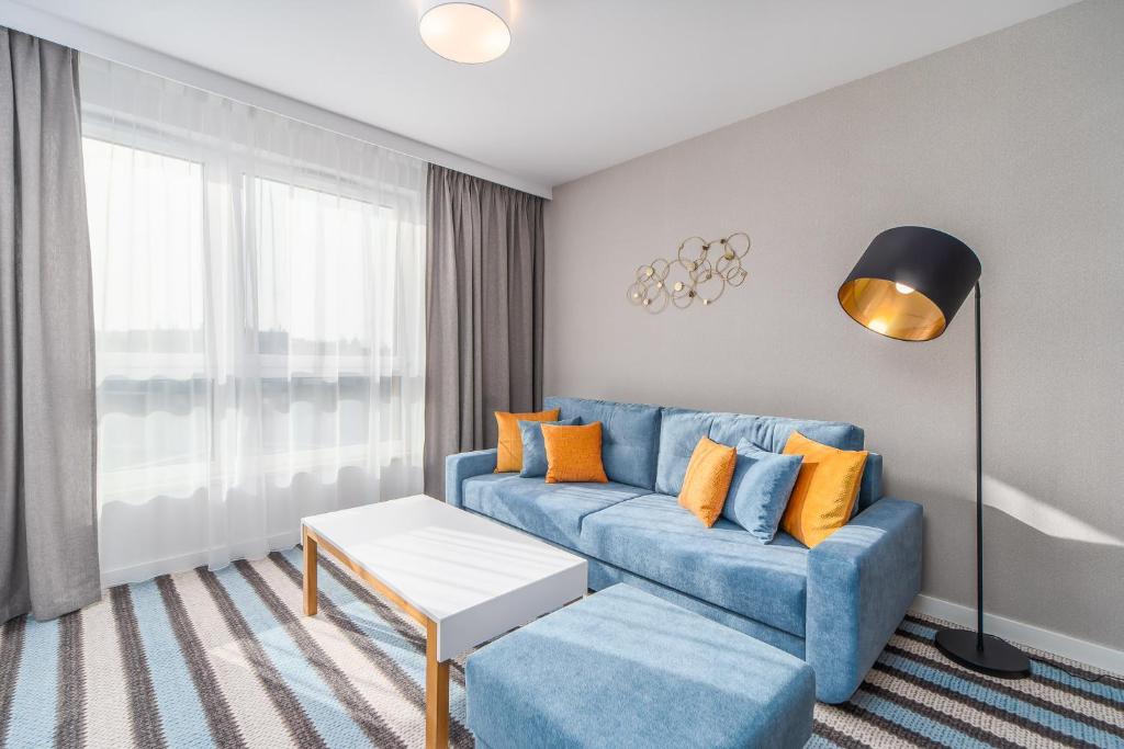 Sunny Apartments in Bel Mare Resort by Renters في مينززدرويه: غرفة معيشة مع أريكة زرقاء ووسائد برتقالية