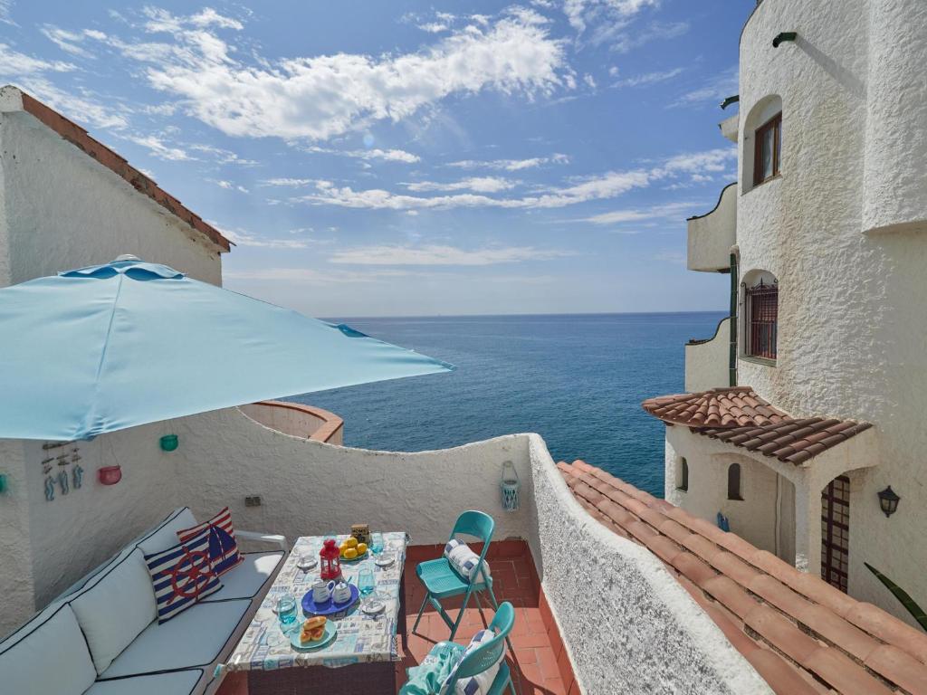 een balkon met een tafel en een blauwe parasol bij Azur Window in Sitges