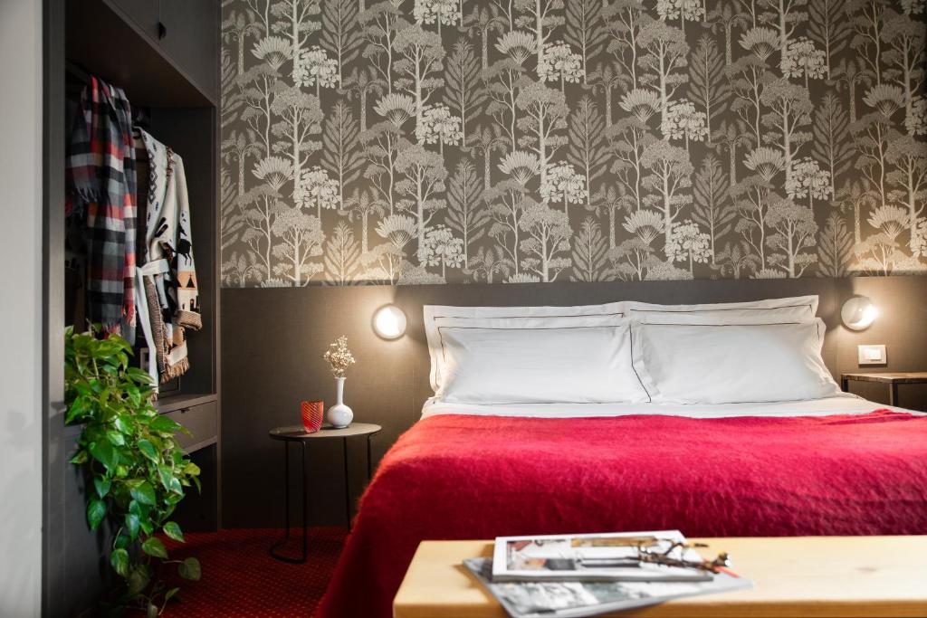 a bedroom with a red bed with a floral wallpaper at Hotel Tremoggia in Chiesa in Valmalenco