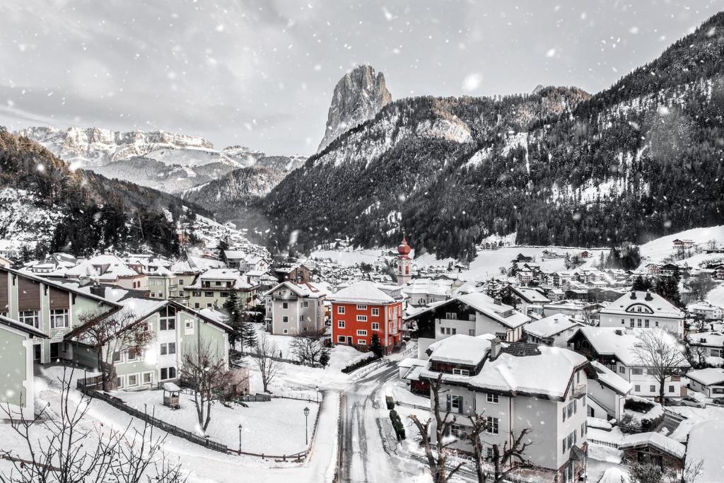 a village covered in snow with a mountain in the background at Casa al Sole in Ortisei