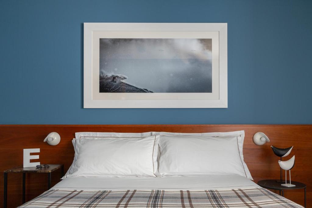 a bed with a blue wall with a picture above it at Hotel Tremoggia in Chiesa in Valmalenco