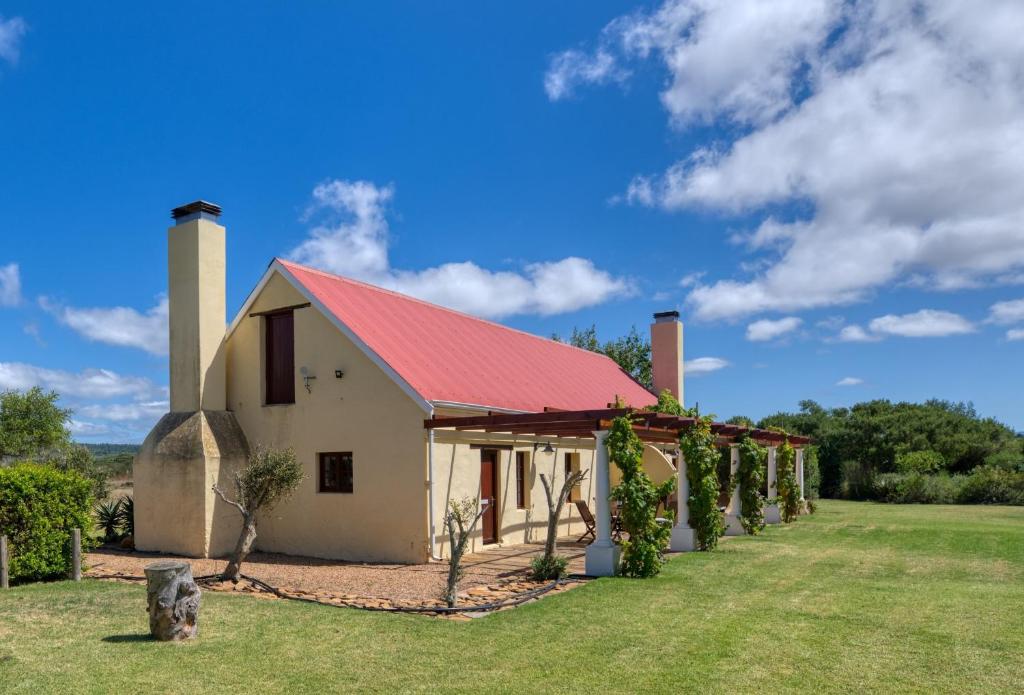 a farm building with a red roof and vines at Strandveld Vineyards Cottages in Elim