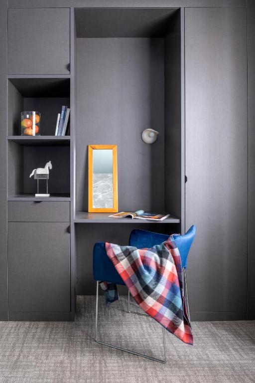 a room with a desk and a blue chair with a pillow at Hotel Tremoggia in Chiesa in Valmalenco