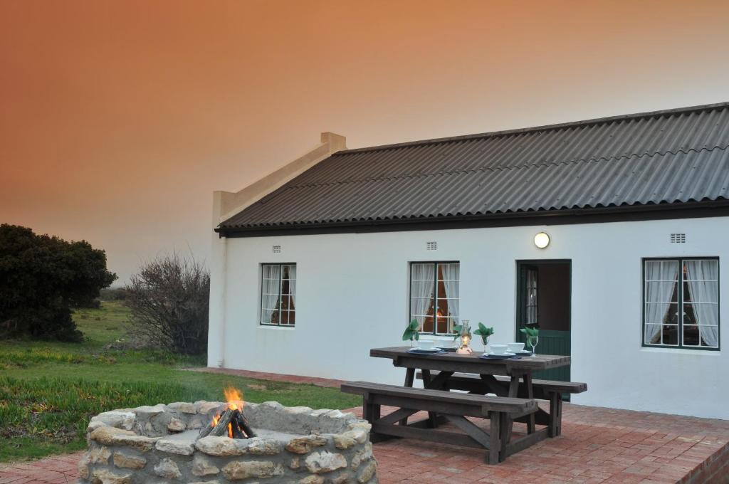 a white house with a picnic table and a fire pit at De Hoop Collection - Village Cottages in De Hoop Nature Reserve