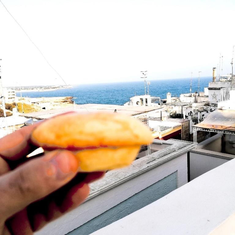 a person holding a donut in front of the ocean at FONTEblu B&B in Polignano a Mare