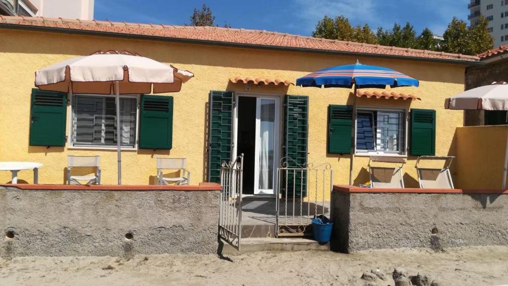 uma casa amarela com guarda-sol e cadeiras em Villino ida em Follonica