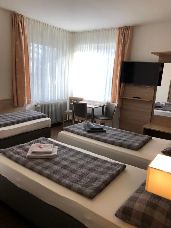 een hotelkamer met 3 bedden en een bureau bij Hotel Baccara in Aken