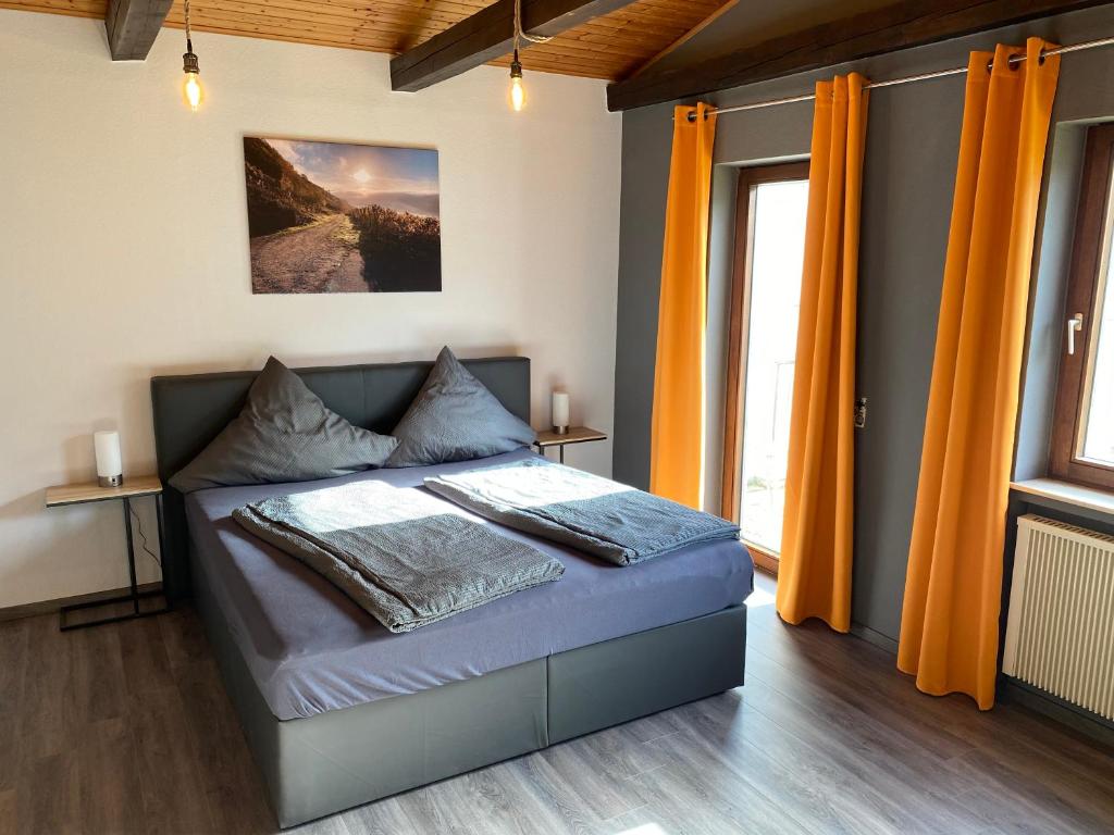 Schlafzimmer mit einem Bett mit orangefarbenen Vorhängen in der Unterkunft Ferienweingut Peter-Jos. Hauth in Bernkastel-Kues