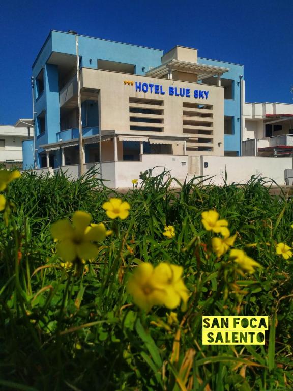 a hotel building with yellow flowers in front of it at Hotel Blue Sky - San Foca in San Foca