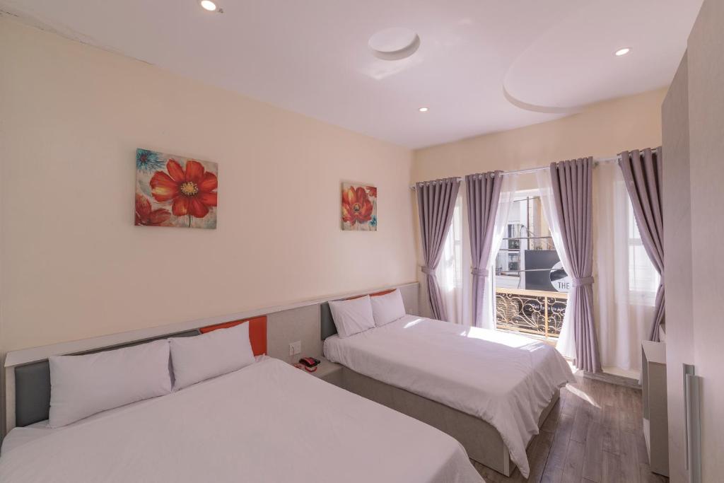 due letti in una piccola stanza con una finestra di Tường Vy 2 Hotel a Da Lat