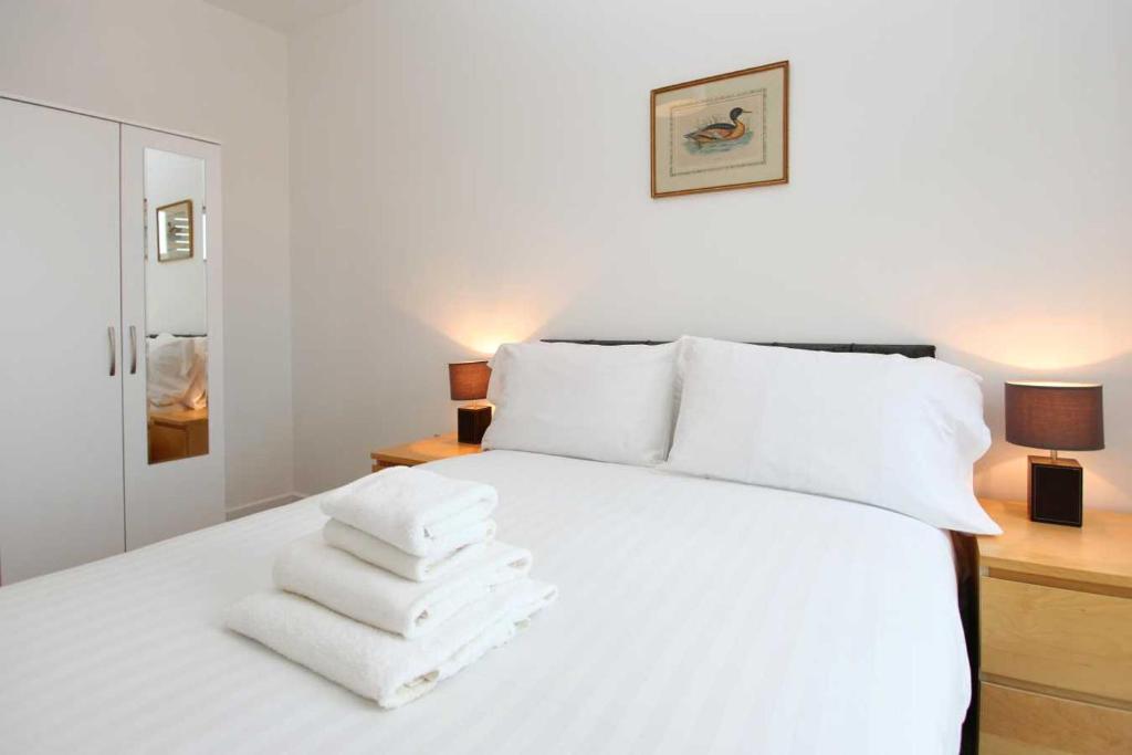 a bedroom with a white bed with towels on it at Parkes Court Apartments in Telford