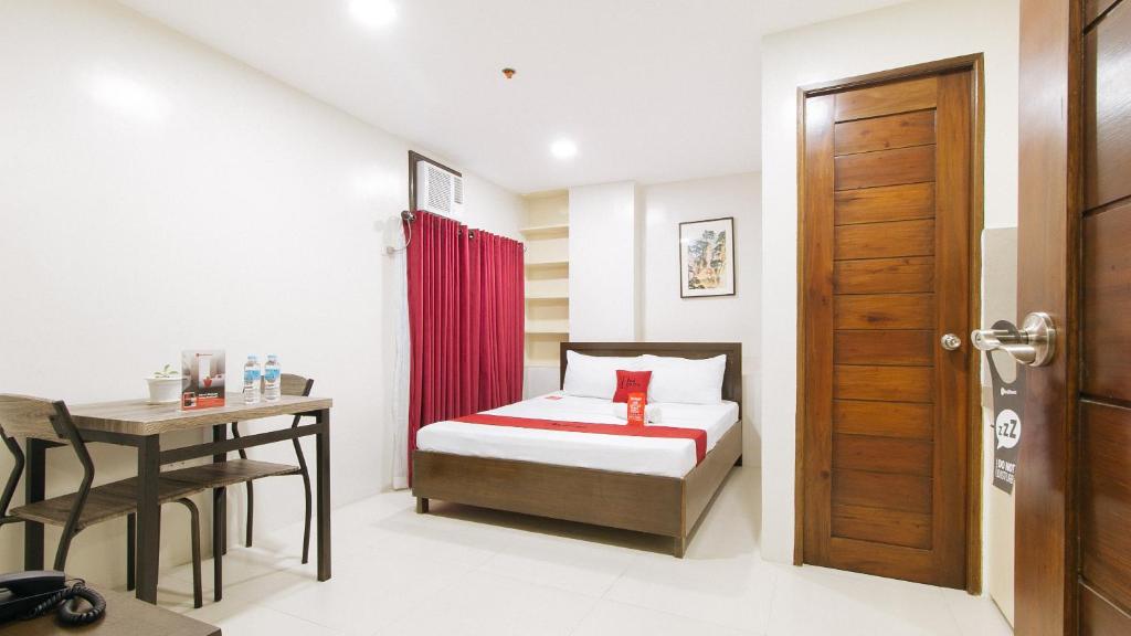 a bedroom with a bed and a desk and a door at RedDoorz near Fernwoods Garden Quezon City in Manila