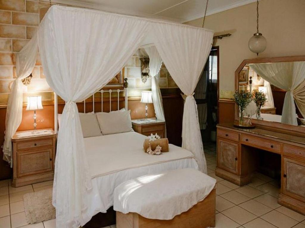 a bedroom with a canopy bed with a teddy bear on it at Coco Cabana Guest House in Pongola