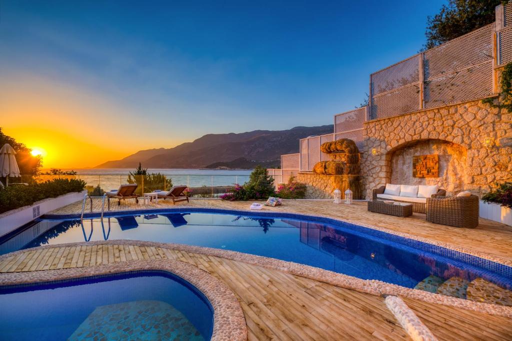 ein Pool vor einem Haus mit Sonnenuntergang in der Unterkunft Peninsula Gardens Hotel in Kaş