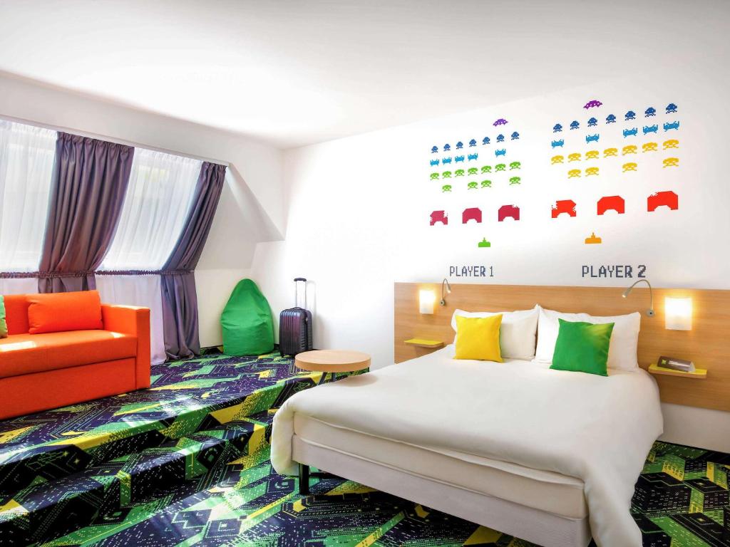 a hotel room with a bed and an orange chair at Ibis Styles Budapest Center in Budapest
