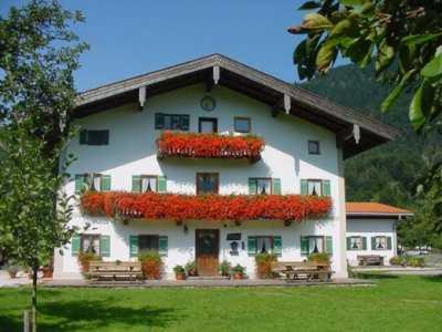 ein großes weißes Gebäude mit roten Blumen drauf in der Unterkunft Gschwendtner-Hof Ferienhof mit Wildgehege in Schleching