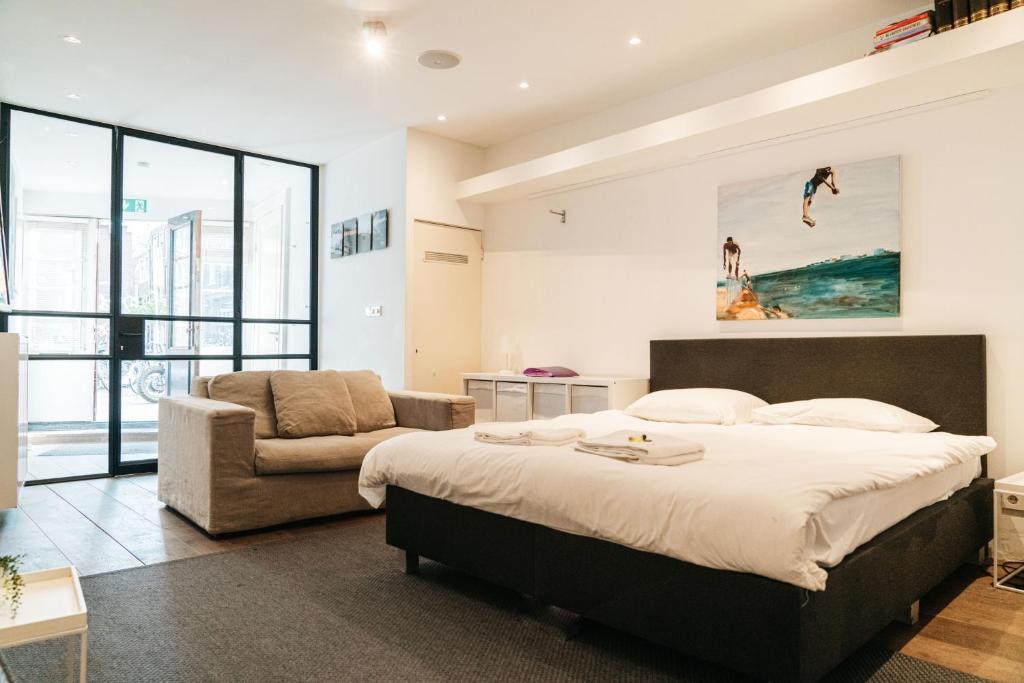 a bedroom with a large bed and a couch at Spui apartment in center in Amsterdam