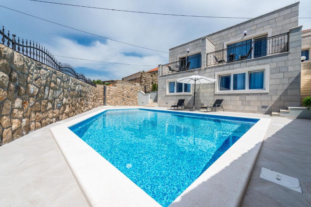 a swimming pool in front of a house at Apartments Villa Kabalero in Gruda