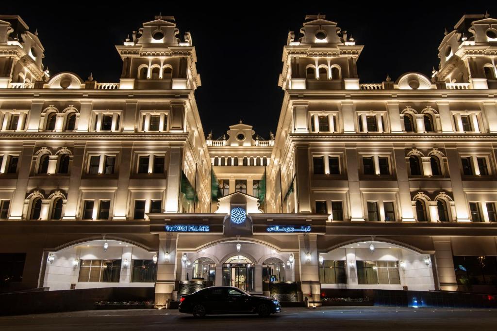 利雅德的住宿－Vittori Palace Hotel and Residences，夜间停在大楼前的汽车