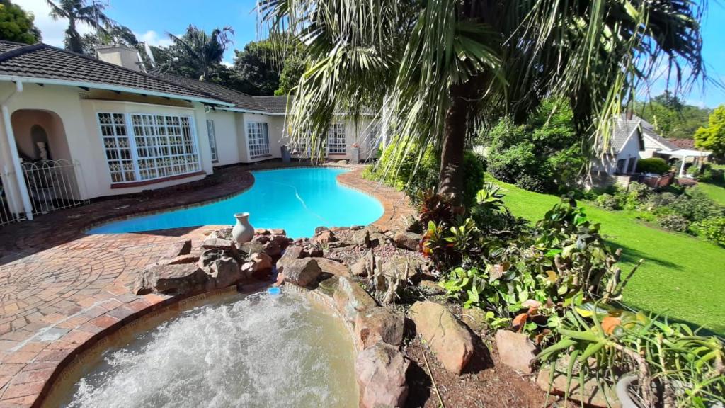 a swimming pool with a waterfall in a yard at Queenz Bed & Breakfast in Durban