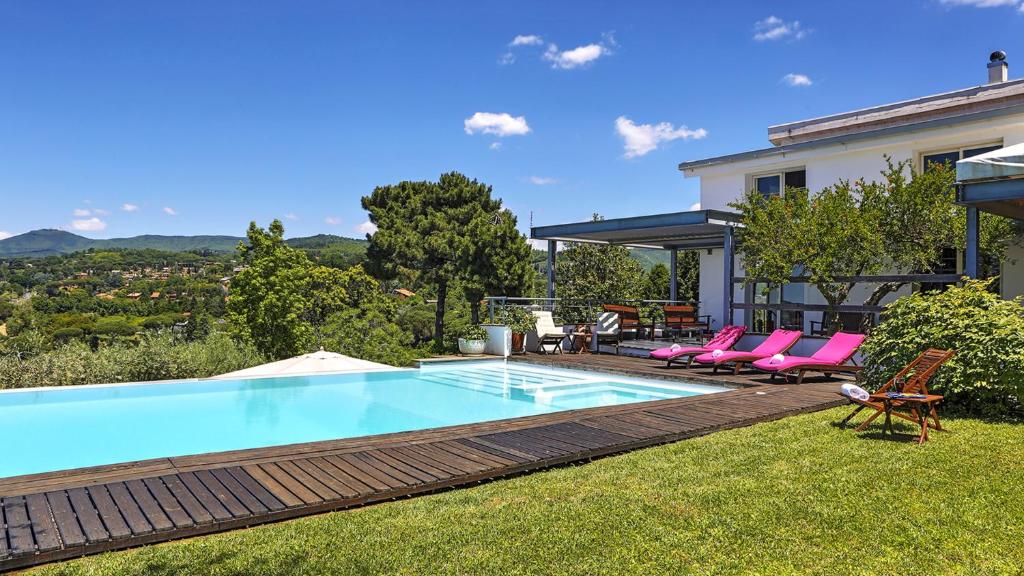 a swimming pool with pink chairs and a house at LANUVIUM 10, Emma Villas in Lanuvio