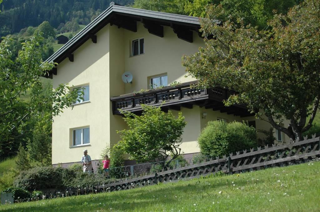 duży żółty dom z ludźmi stojącymi przed nim w obiekcie Ferienwohnung Hildegard w mieście Silbertal