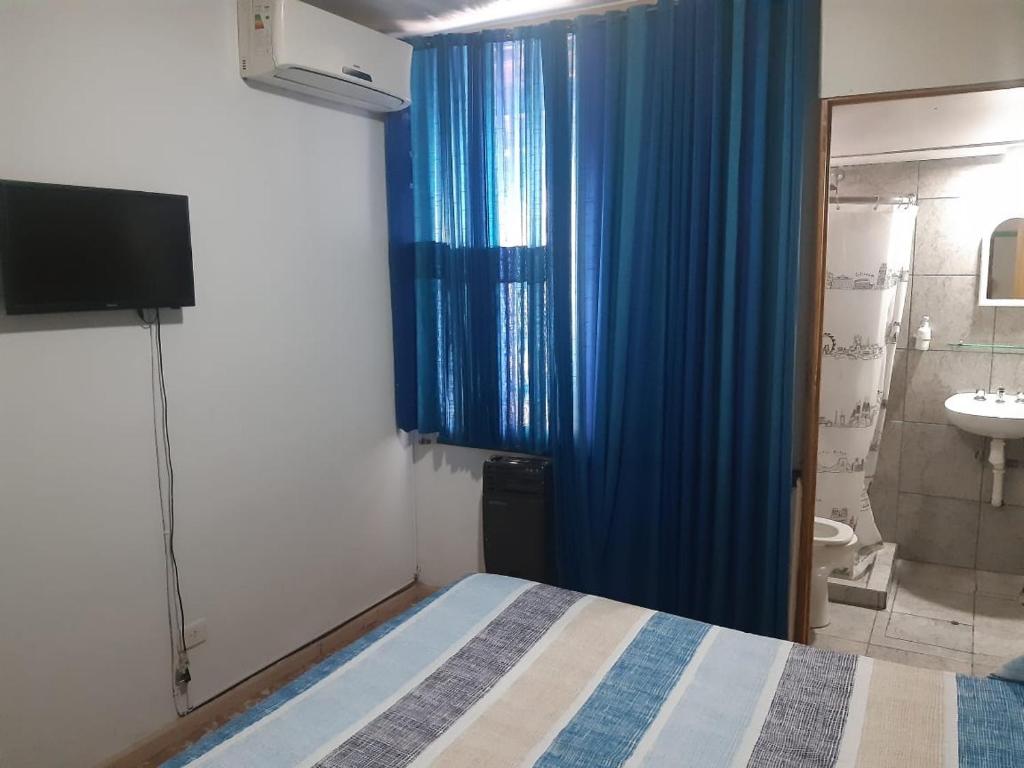 um quarto com uma cama e uma casa de banho com um lavatório em Hostel Otro Mundo em Mendoza