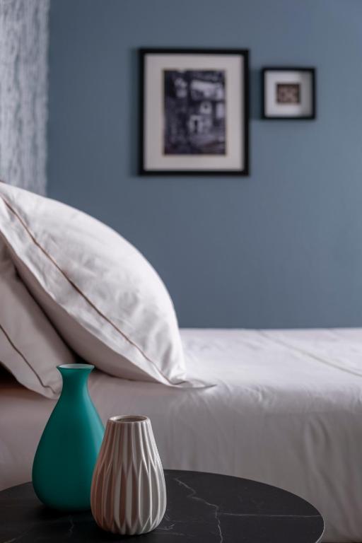 a bed with white pillows and a green vase on a table at Hotel Tremoggia in Chiesa in Valmalenco