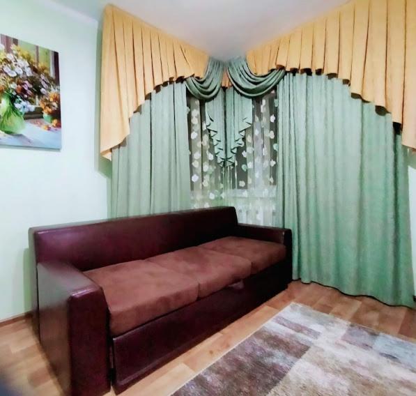 a couch in a living room with green curtains at Апартаменты Харьковская in Sumy