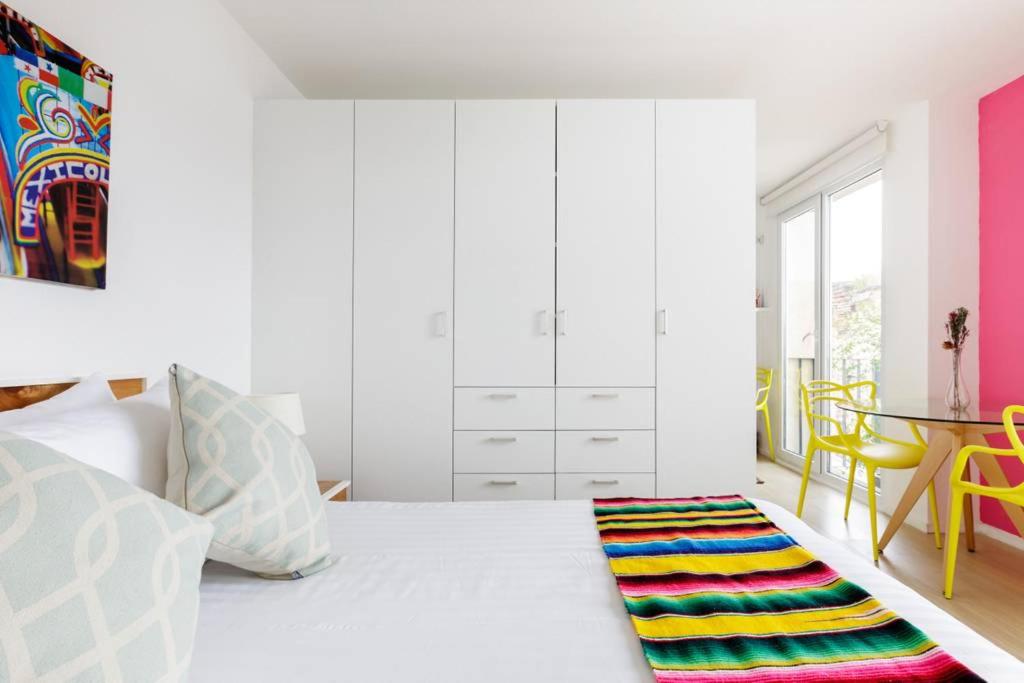 1 dormitorio con cama blanca y alfombra colorida en el suelo en MyPlace at Santo Domingo, en Ciudad de México